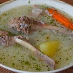 Caldo de cordero con arroz, papa, zanahoria y culantro servido caliente en plato hondo