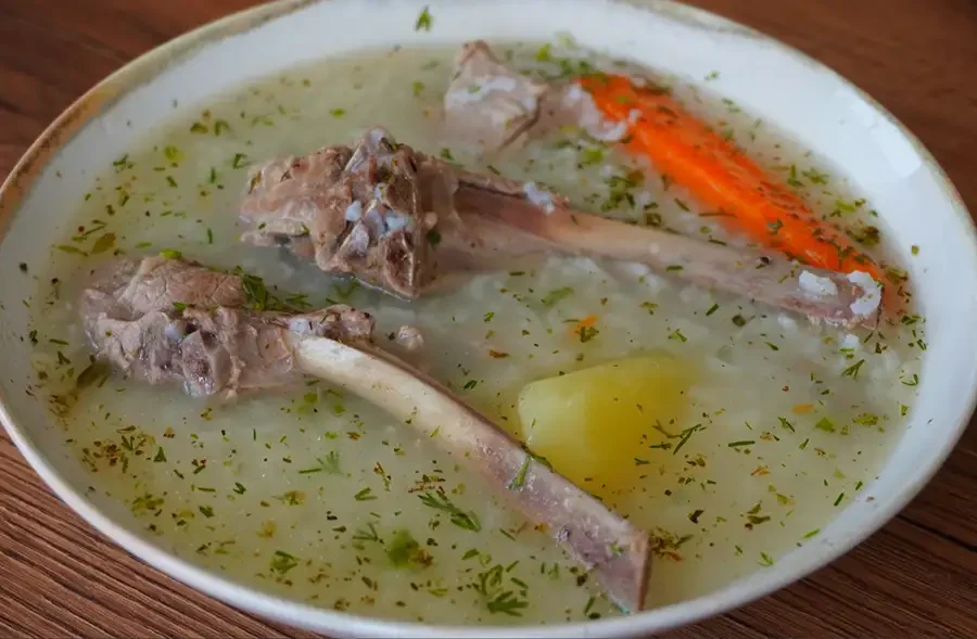 Caldo de cordero con arroz, papa, zanahoria y culantro servido caliente en plato hondo