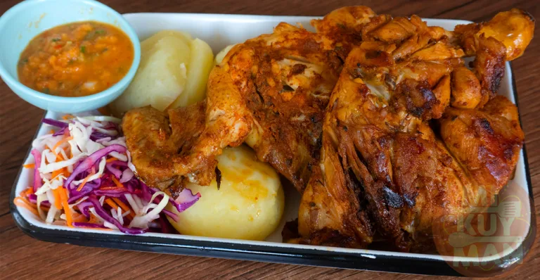 Un plato tradicional de pollada peruana con pollo, papas, ensalada y ají.