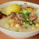 Un plato humeante de Charqui Caldo, con carne, papas, garbanzos y verduras en un caldo sabroso.