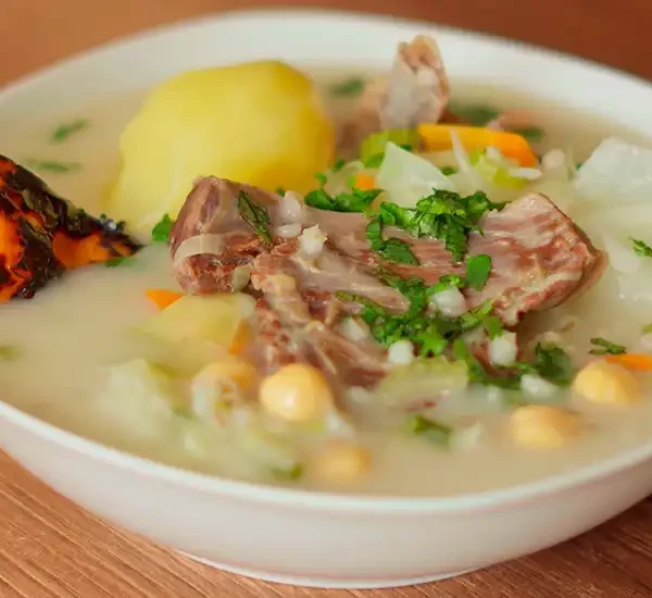 Un plato humeante de Charqui Caldo, con carne, papas, garbanzos y verduras en un caldo sabroso.