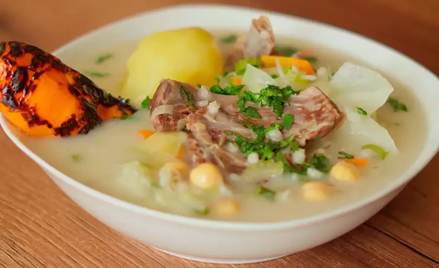 Un plato humeante de Charqui Caldo, con carne, papas, garbanzos y verduras en un caldo sabroso.