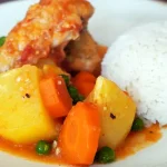 Plato de Estofado de Pollo Peruano servido con papas y arroz
