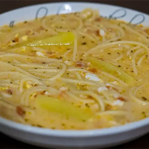 Sopa de leche con fideos, papas y huevo deshecho servida caliente y cremosa