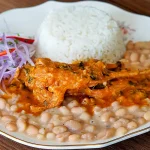 Cabrito a la Norteña servido con arroz y frijoles, plato típico de la cocina peruana