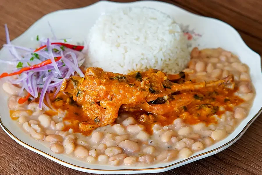 Cabrito a la Norteña servido con arroz y frijoles, plato típico de la cocina peruana