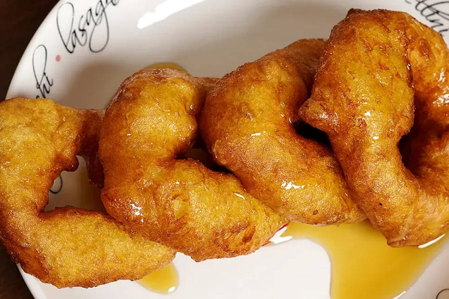 Picarones Peruanos con miel casera servidos en un plato - Postre tradicional peruano.