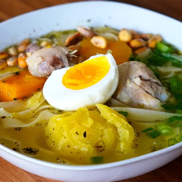 Caldo de Pollo Tradicional Peruano servido con verduras, fideos y cebolla china picada