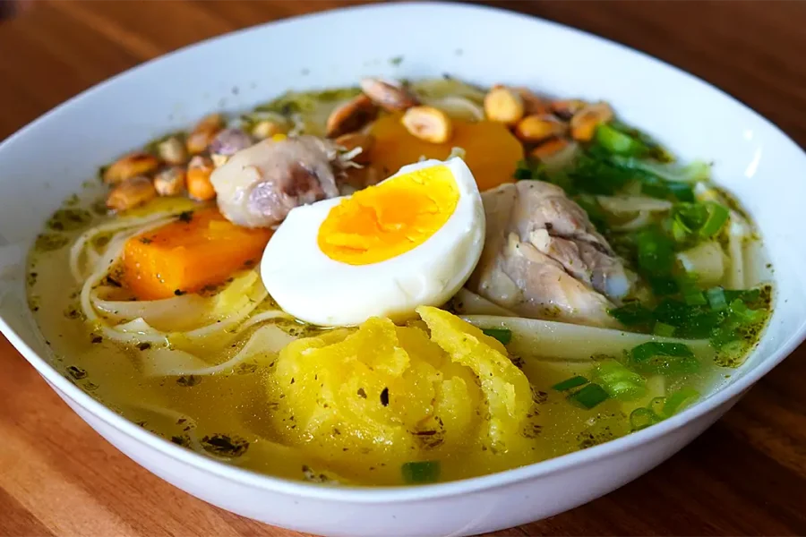 Caldo de Pollo Tradicional Peruano servido con verduras, fideos y cebolla china picada