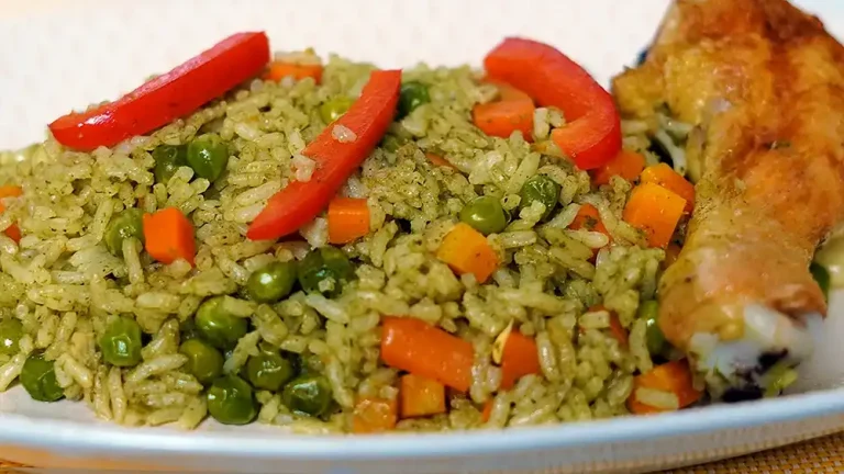 "Plato de arroz con pollo peruano con arroz verde, arvejas, zanahorias y pimiento rojo
