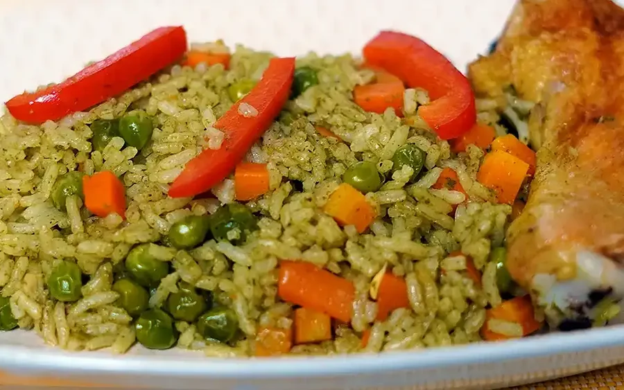 "Plato de arroz con pollo peruano con arroz verde, arvejas, zanahorias y pimiento rojo