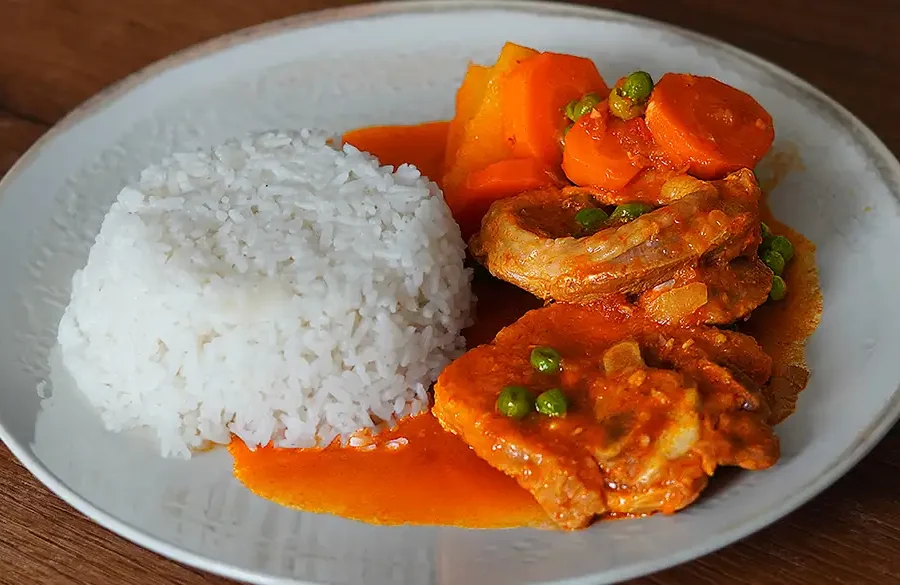 Plato de estofado de pavita con papas, zanahorias y arvejas, servido en un plato hondo.