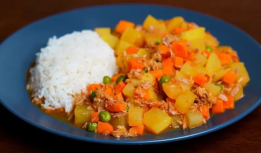Guiso de Atún Peruano con papas y alverjas servido en un plato caliente