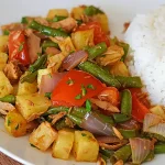 Saltado de atún con papas fritas y vainitas servido en un plato blanco