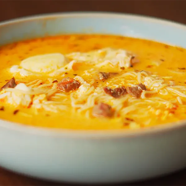 sopa a la minuta peruana casera servida en un plato hondo con huevo escalfado y orégano