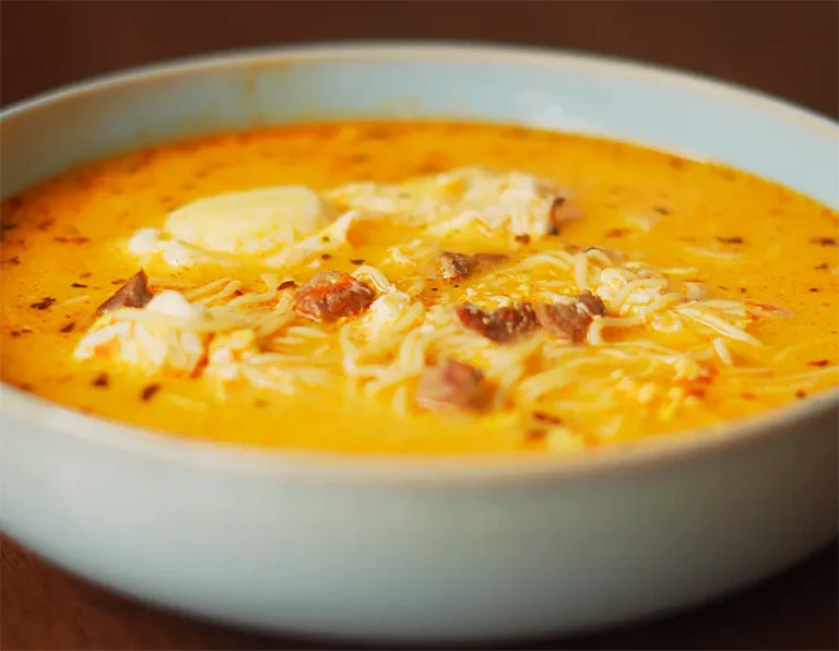 sopa a la minuta peruana casera servida en un plato hondo con huevo escalfado y orégano