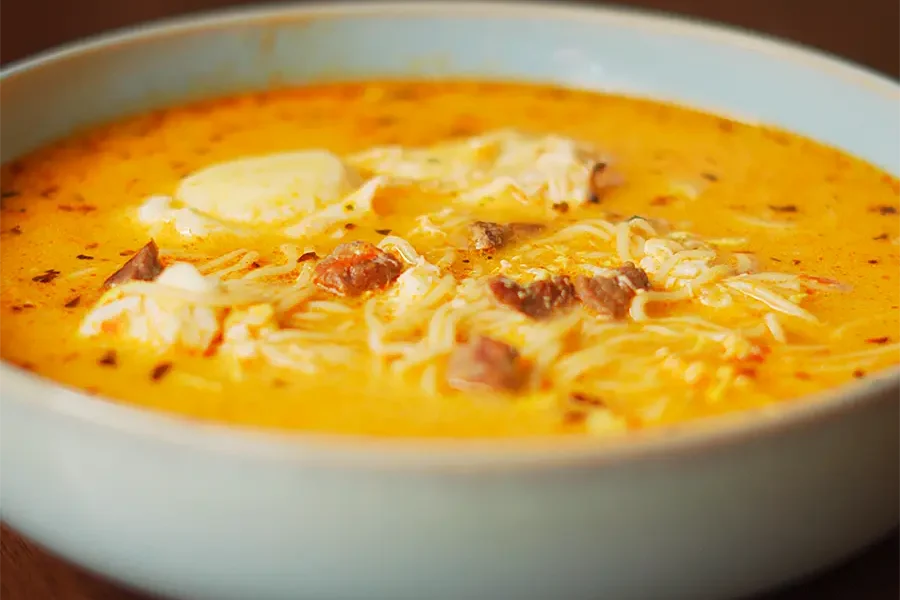sopa a la minuta peruana casera servida en un plato hondo con huevo escalfado y orégano