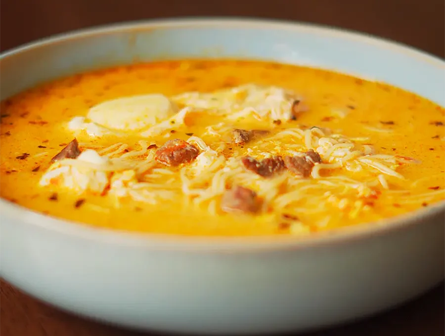 sopa a la minuta peruana casera servida en un plato hondo con huevo escalfado y orégano