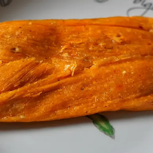 Tamales peruanos tradicionales de maíz rellenos de pollo, aceituna y huevo, envueltos en hojas de plátano.