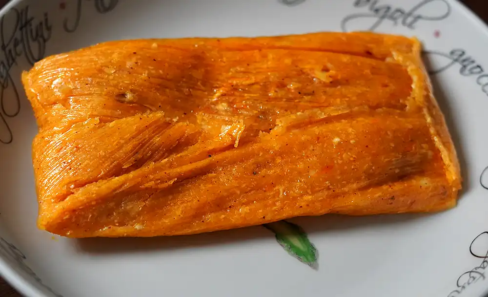 Tamales peruanos tradicionales de maíz rellenos de pollo, aceituna y huevo, envueltos en hojas de plátano.