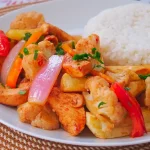 Saltado de coliflor con pollo peruano servido con papas doradas y verduras salteadas