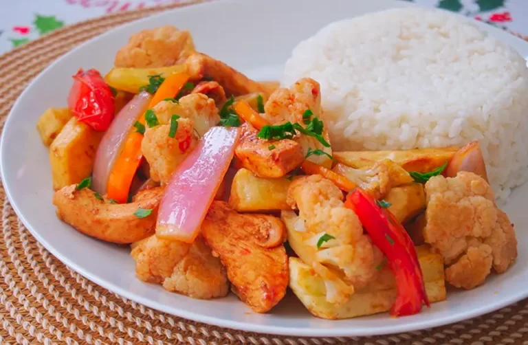 Saltado de coliflor con pollo peruano servido con papas doradas y verduras salteadas